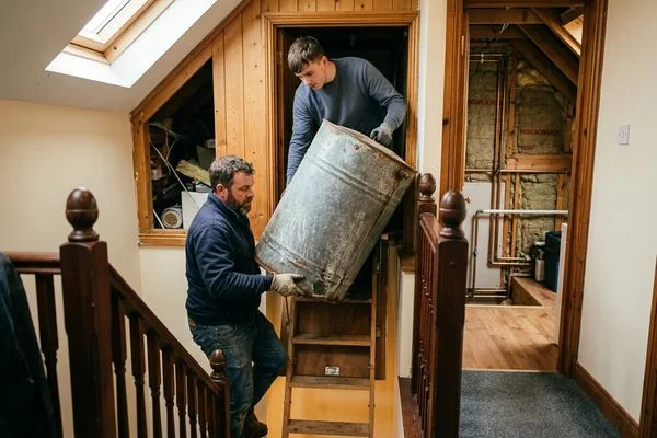 Old galvanised steel water tank being removed from an attic during replacement